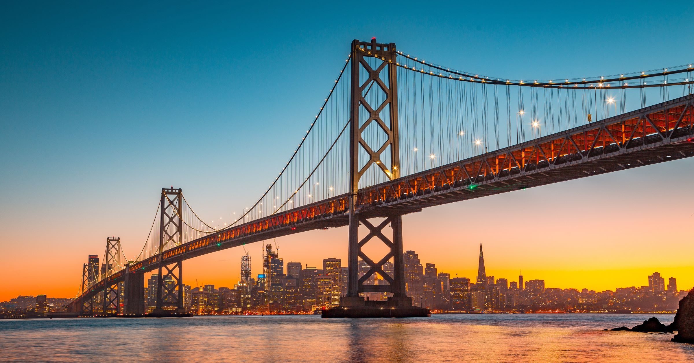 Die berühmte Golden Gate Brücke im Sonnenuntergang vor der Wolkenkratzer Silhouette von San Francisco